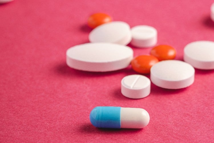 Pills and tablets on pink background