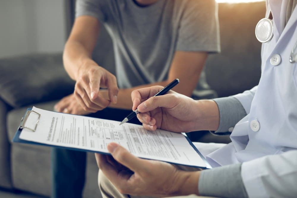 Patient is diagnosed with the effects of the disease and is pointing to the doctor report and discussing the effects.