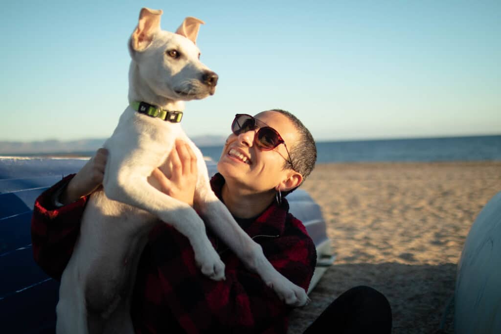 woman with sunglasses and her dog at the beach