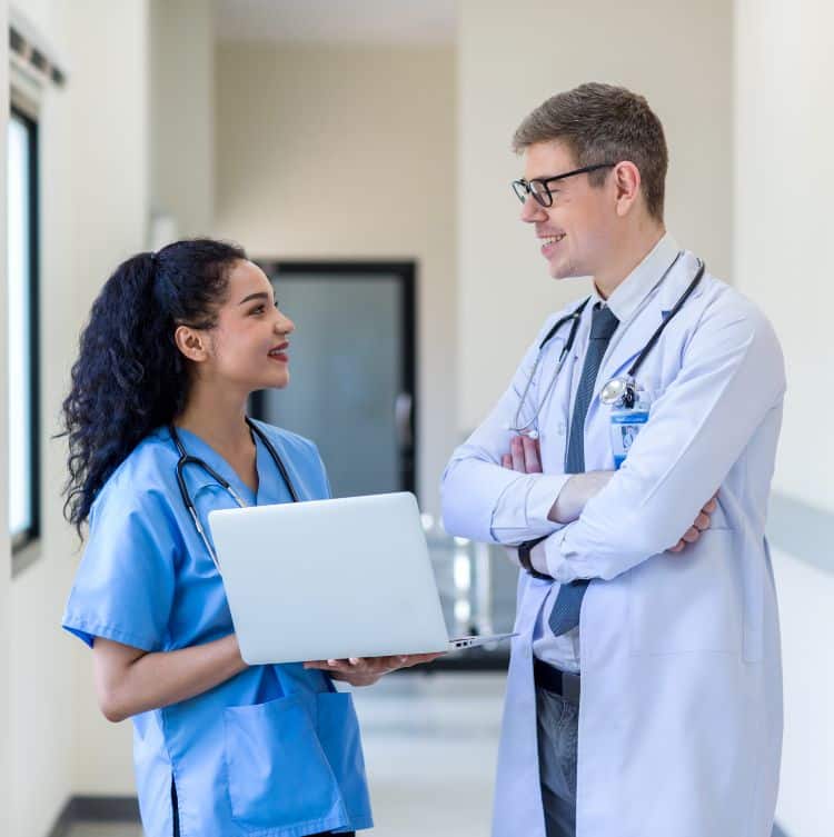 Clinicians in uniform standing and looking of computer monitor