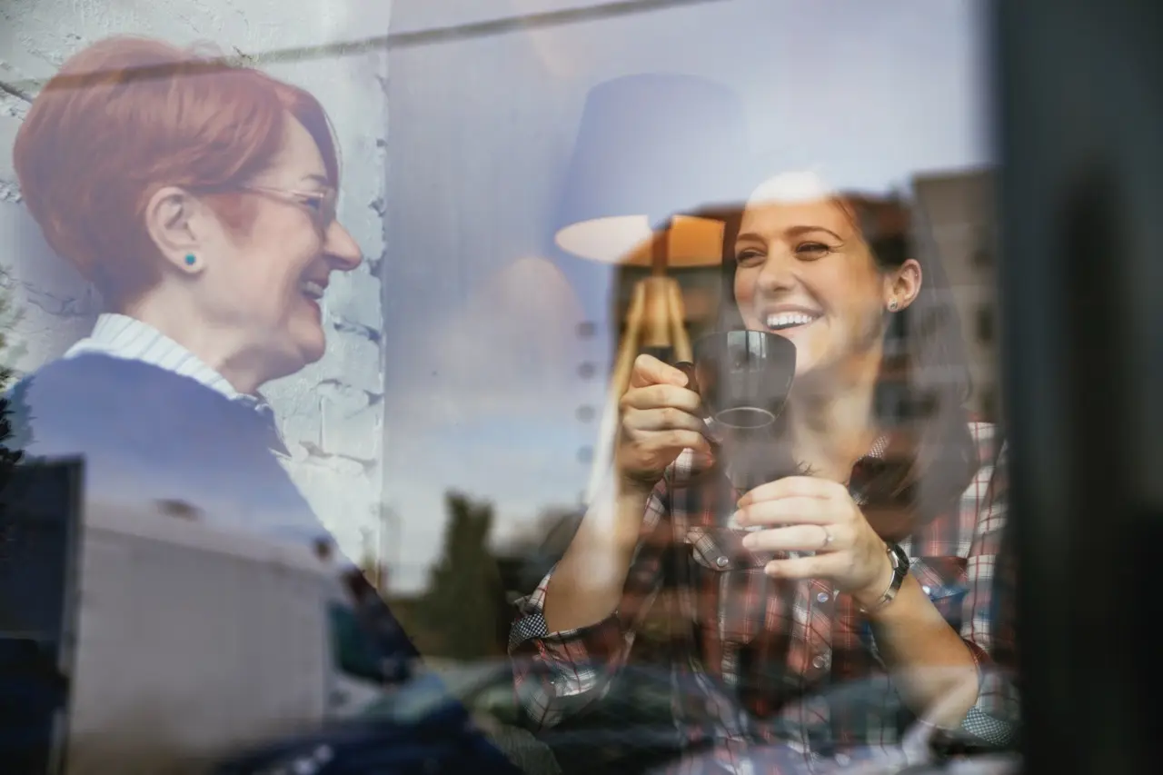 A happy adult with her mother in a cafe. They're both smiling and enjoying a conversation